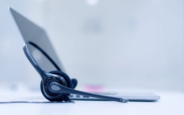 Selective focus photo of a headset beside a laptop on a table