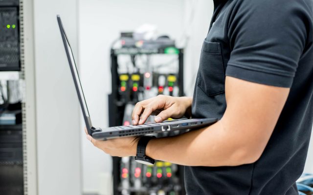 A person working on a laptop in a computer server room